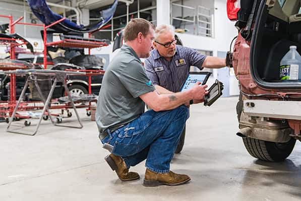 Two Anderson-Weber ABRA repair specialists examining a vehicle in the body shop