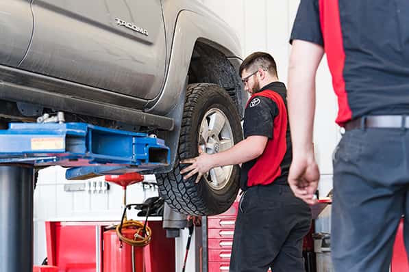 Anderson-Weber technicians working on the wheel of a Toyota Tacoma in the service shop